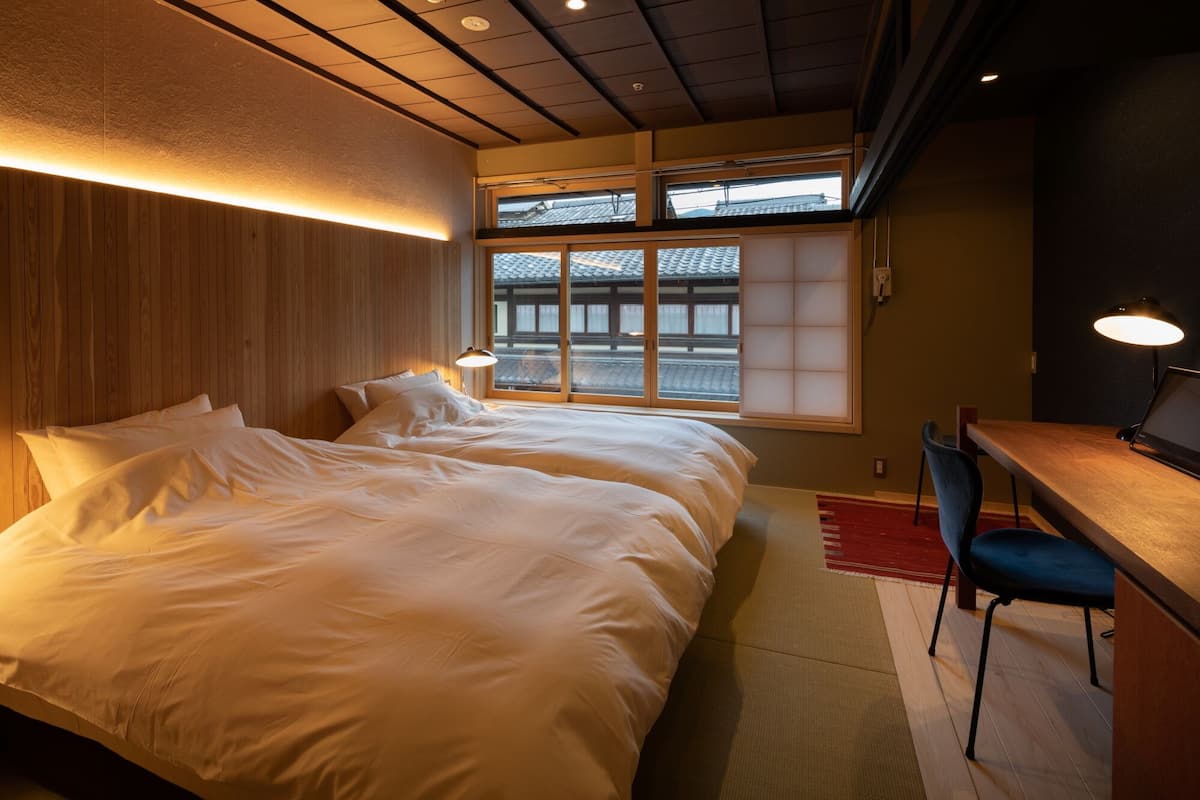 A hotel room with two beds, a desk, and a chair.