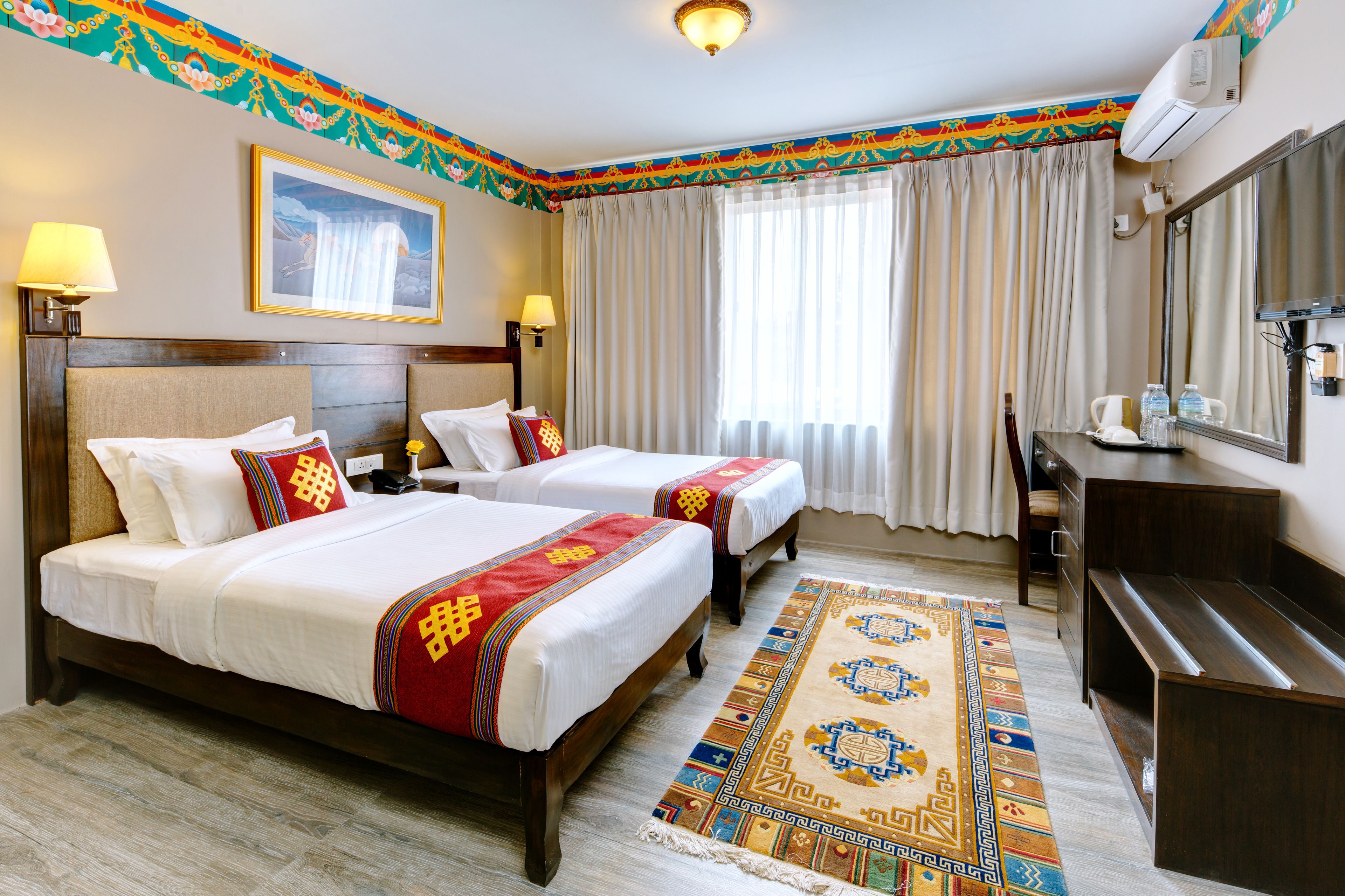 A hotel room with two beds, a large mirror, a desk, and a decorative rug.