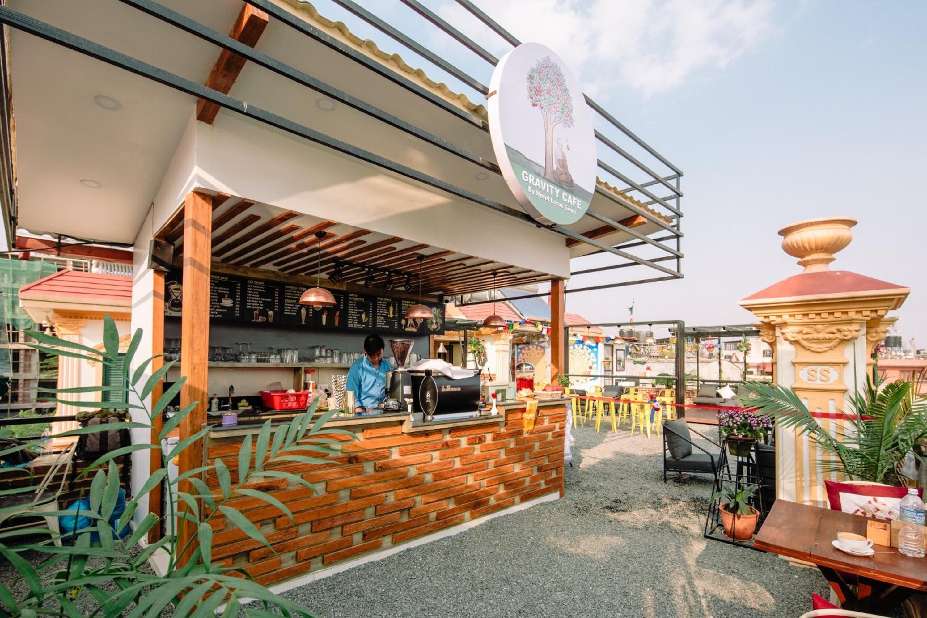 Un café al aire libre con una barra de madera rústica, una máquina de café y un panel con la carta.