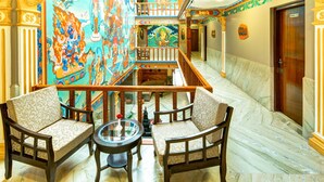 A hotel lobby with a central seating area, a staircase, and a mural. - Hotel Lotus Gems (Kathmandu)