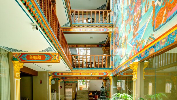 A multi-level atrium with ornate railings, a central staircase, and a large mural. - Hotel Lotus Gems (Kathmandu)