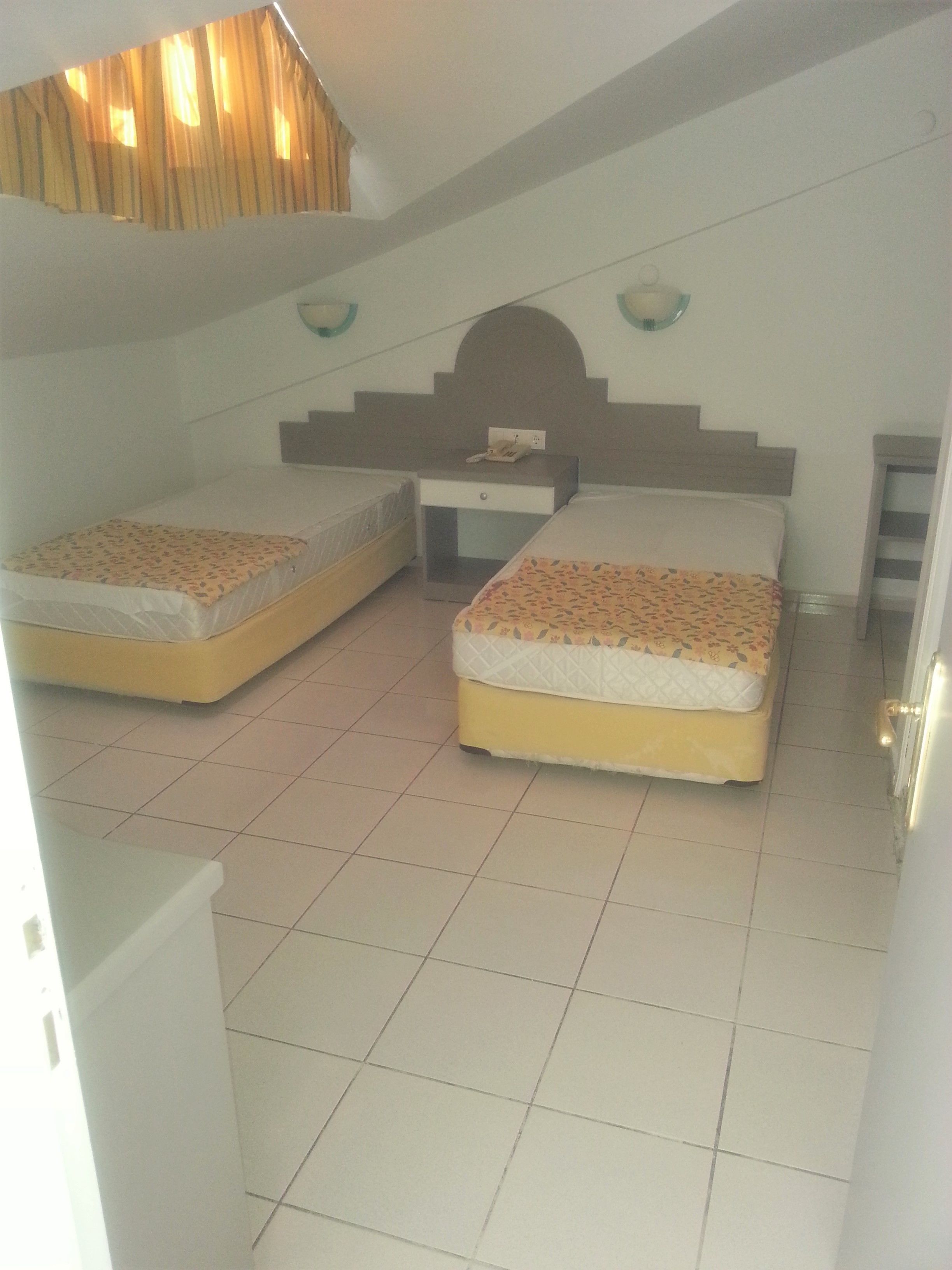 A bedroom with two beds, a nightstand, and a small table.