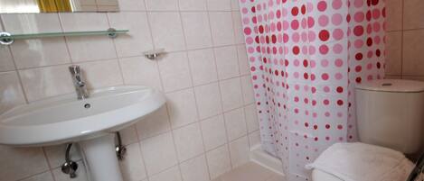 A bathroom with a white sink, a toilet, and a shower curtain with pink polka dots.