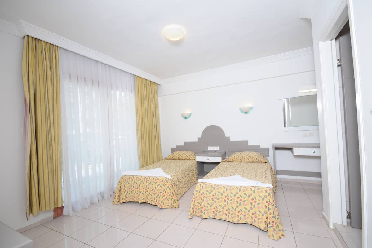A hotel room with two beds, a desk, and a mirror.