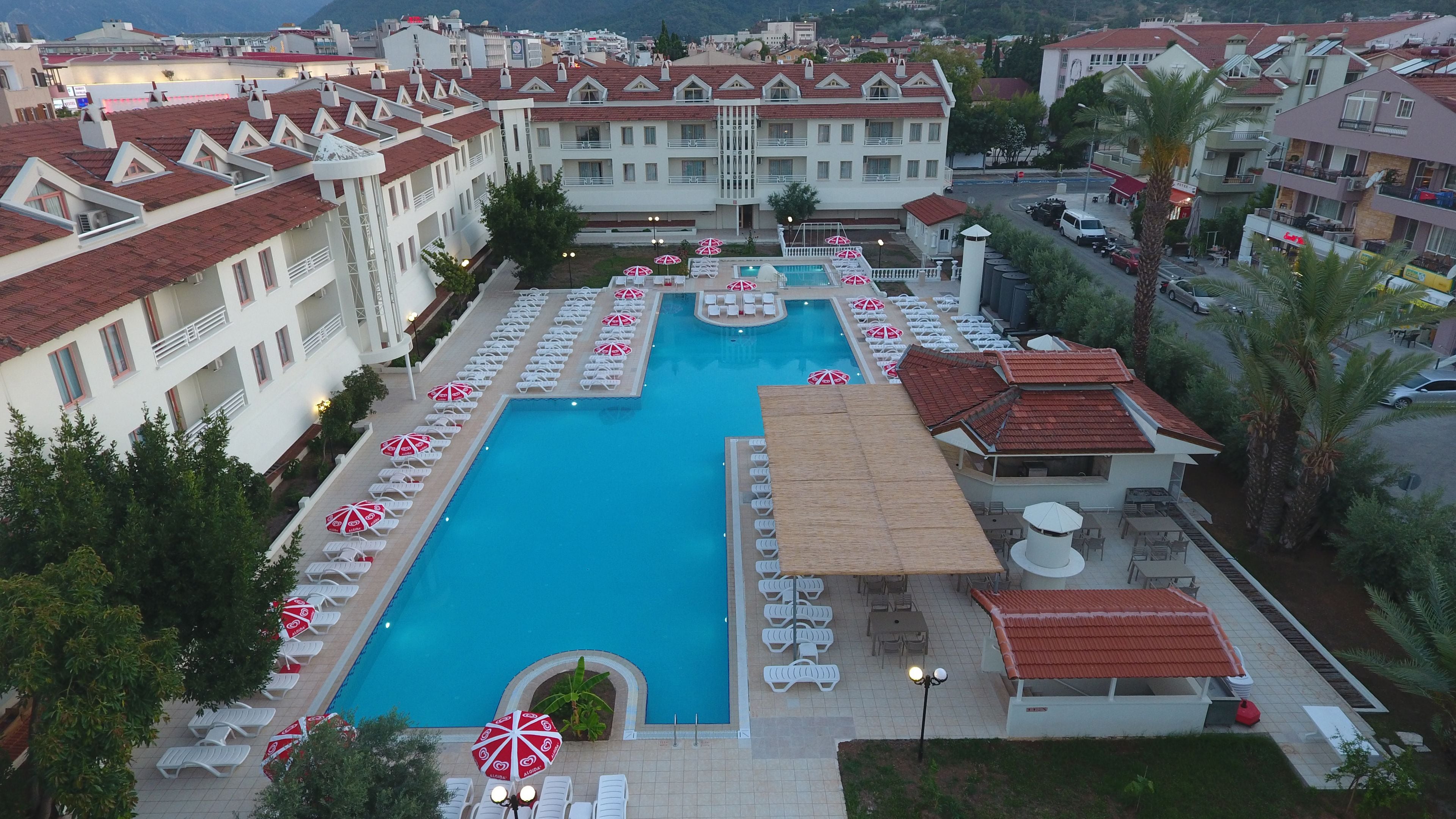 A large swimming pool surrounded by lounge chairs and umbrellas, with a view of the surrounding buildings.