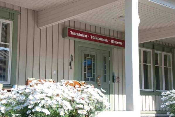 A building with a sign reading "Tervetulon · Välkommen · Welcome!" and a door with a mailbox.