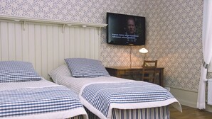 Une chambre avec deux lits, un téléviseur fixé au mur, un bureau et une chaise.