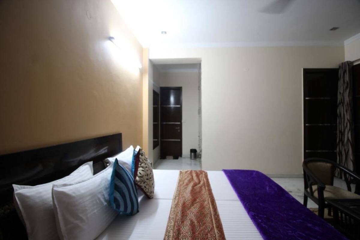Ein Schlafzimmer mit Bett, Kissen, Decke, einem Sessel und einem Kleiderschrank.