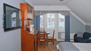 Una habitación de hotel con cama, escritorio con cafetera, televisor y vistas al exterior.