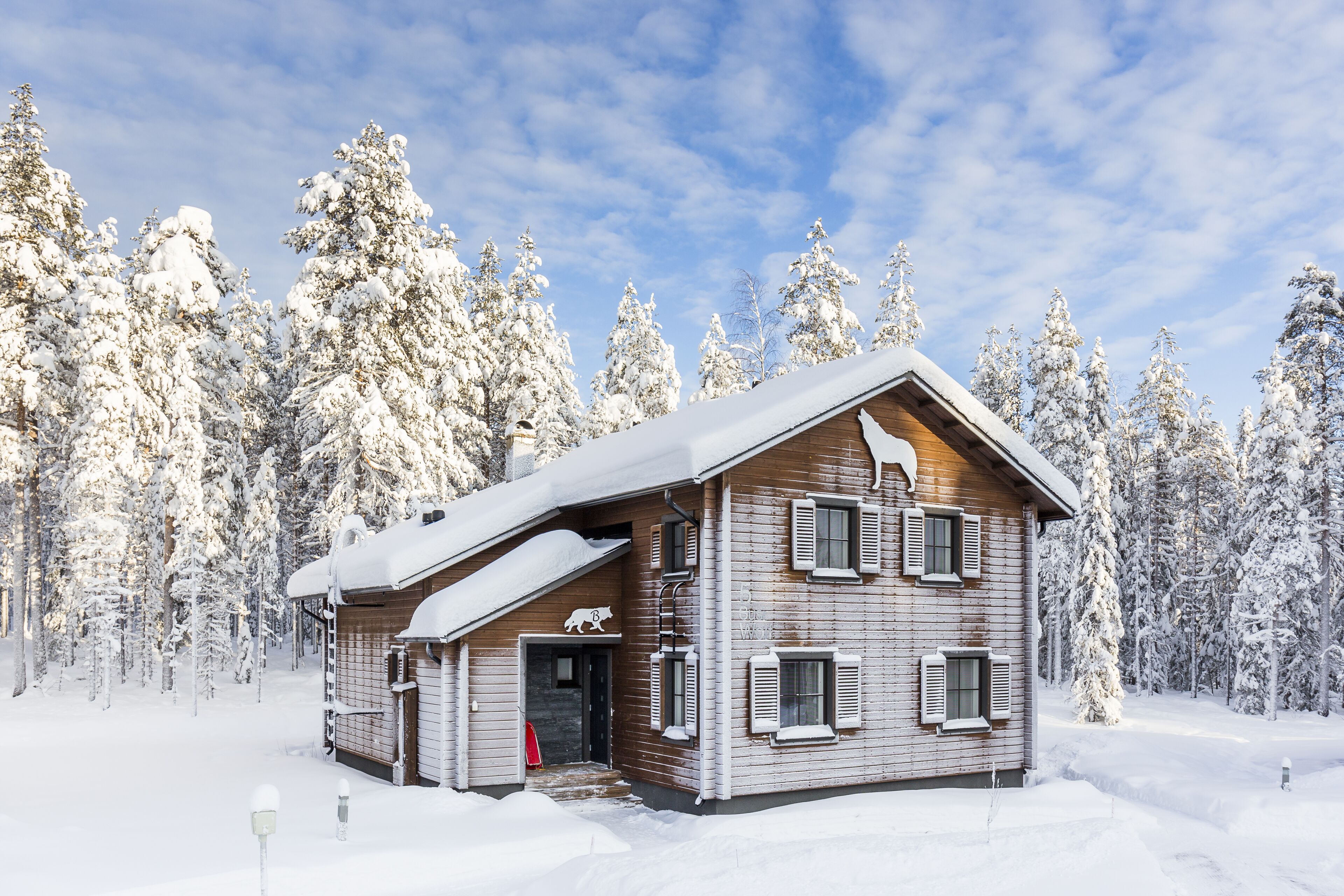 Eine Holzhütte mit geneigtem Dach, umgeben von schneebedeckten Bäumen.