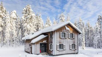 Eine Holzhütte mit geneigtem Dach, umgeben von schneebedeckten Bäumen.