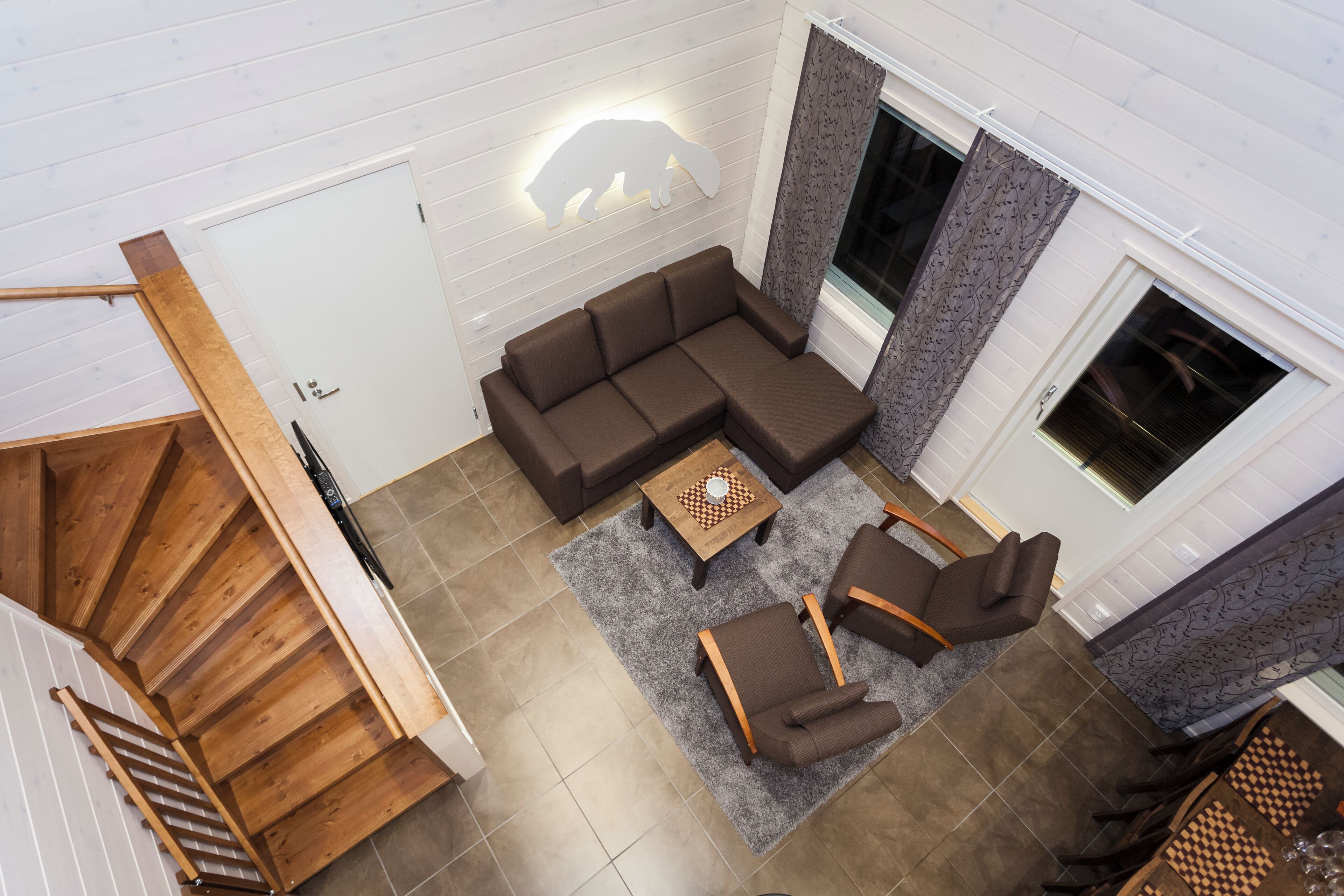 A modern living room with a sectional sofa, a small coffee table, and a chair. There is a staircase with wooden railings leading to another level.