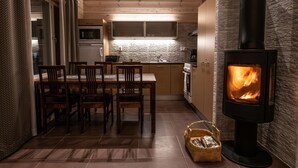 A cozy kitchen with a wood-burning stove, a dining area with chairs, and a kitchen counter. - Ranua Resort Holiday Villas (Ranua)