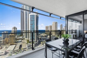A balcony with a city view, a table with chairs, and a potted plant. - Circle on Cavill - Q Stay (Surfers Paradise)