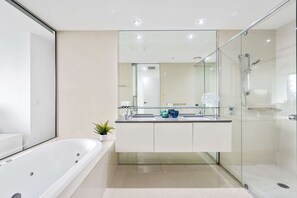 A modern bathroom with a glass-enclosed shower, a freestanding bathtub, and a large mirror above the sink. - Circle on Cavill - Q Stay (Surfers Paradise)