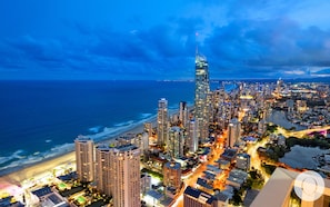 Un grand hôtel à plusieurs étages, situé près d’une plage et d’un plan d’eau.