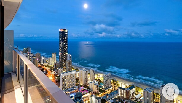 A nighttime cityscape with a prominent skyscraper, a beach, and a view of the ocean. - Circle on Cavill - Q Stay (Surfers Paradise)