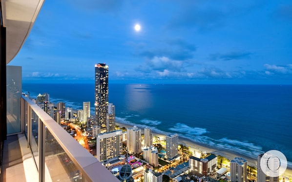 Une vue sur une ville, avec un gratte-ciel imposant, une plage et l’océan à l’horizon.