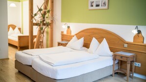 A double bed with white linens, a wooden headboard, a bedside table with a lamp, and a framed picture on the wall. - Gasthaus & Naturparkhotel Linde (Löffingen)