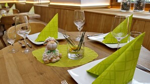 A dining table set with green napkins, wine glasses, and a small decorative sheep figurine. - Gasthaus & Naturparkhotel Linde (Löffingen)