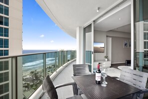 A balcony with a table, chairs, a bottle of wine, and a glass. - H'Residences - Q Stay (Surfers Paradise)