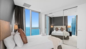 A modern hotel room with a large bed, a mirror, and a view of the ocean. - H'Residences - Q Stay (Surfers Paradise)