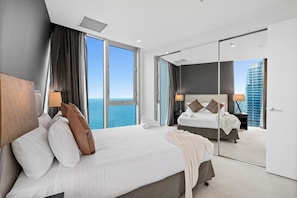 A modern hotel room with a large bed, a mirror, and a view of the ocean. - H'Residences - Q Stay (Surfers Paradise)