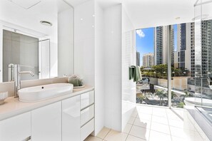 A modern bathroom with a large sink, mirror, and glass shower enclosure. - H'Residences - Q Stay (Surfers Paradise)