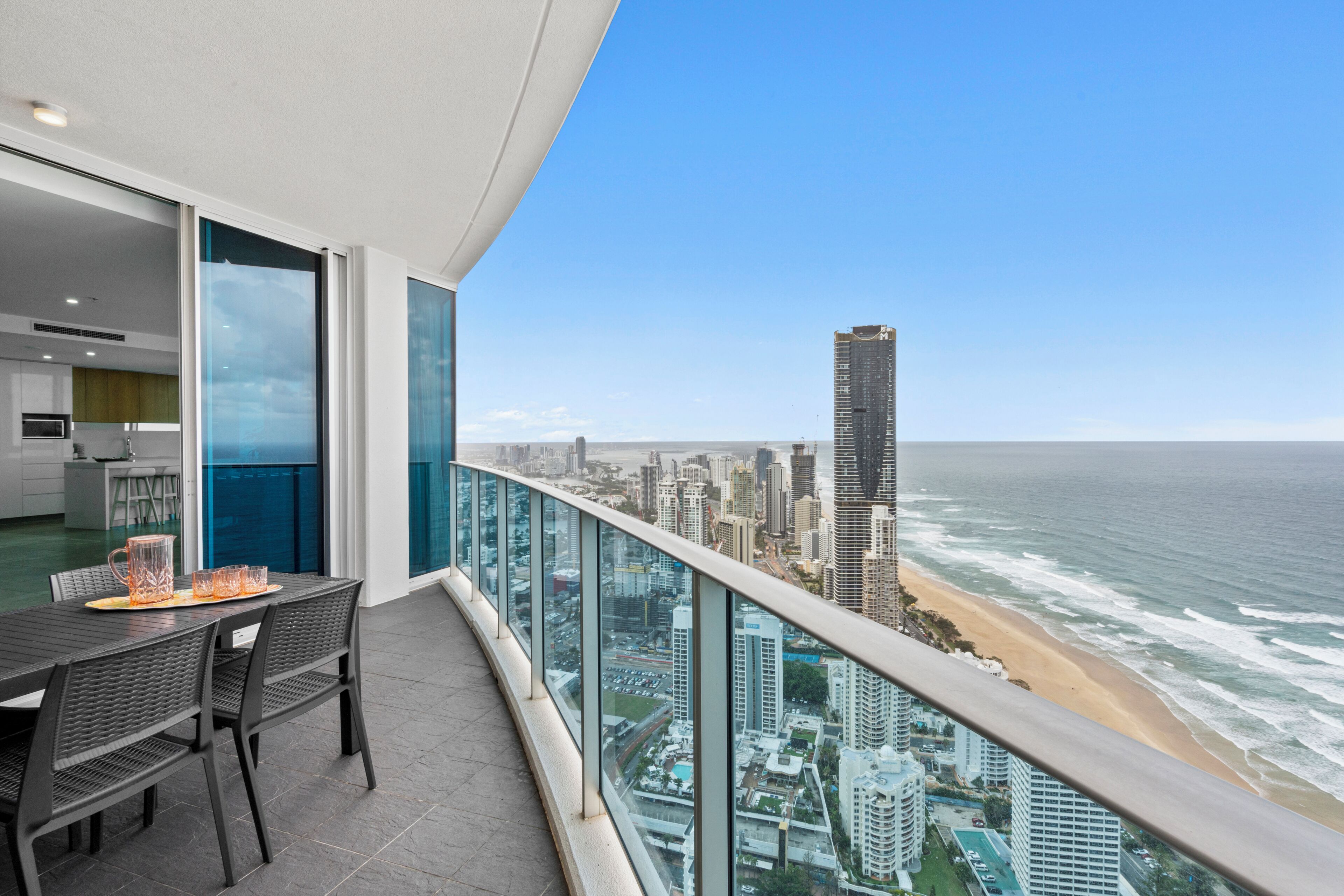 Un balcon avec vue sur la ville et donnant sur l’océan, comprenant un espace repas avec une table et des chaises.