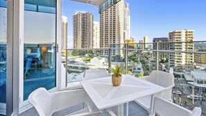 A balcony with white wicker furniture, a small table, and a potted plant.
