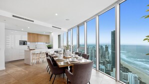 A modern kitchen with white cabinets, a built-in oven, and a large window overlooking the ocean.