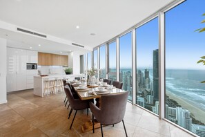 A modern kitchen with white cabinets, a built-in oven, and a large window overlooking the ocean. - H'Residences - Q Stay (Surfers Paradise)