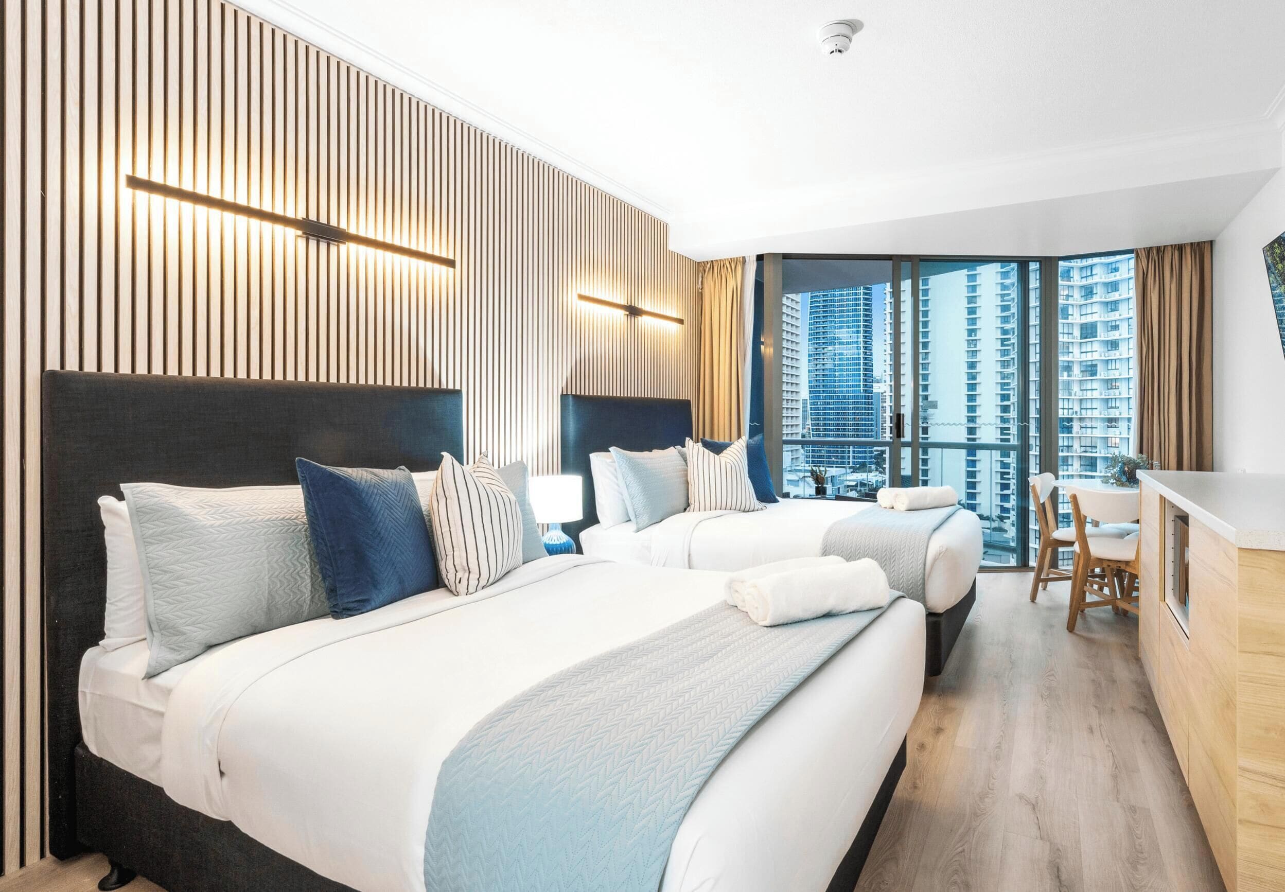 A modern hotel room with a large bed, a desk, and a view of the city.