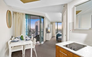 Een moderne hotelkamer met een zithoek, een kitchenette en een groot raam met uitzicht over de stad.