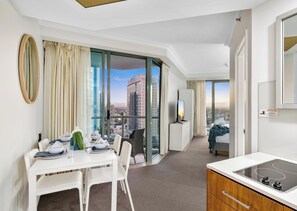 A modern hotel room with a dining area, a kitchenette, and a large window offering a city view. - Legends - Q Stay (Surfers Paradise)