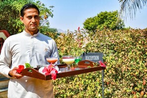 A person holding a tray with drinks and a sign that reads 'RECEPTION'. - Pushkar Resort (Pushkar)