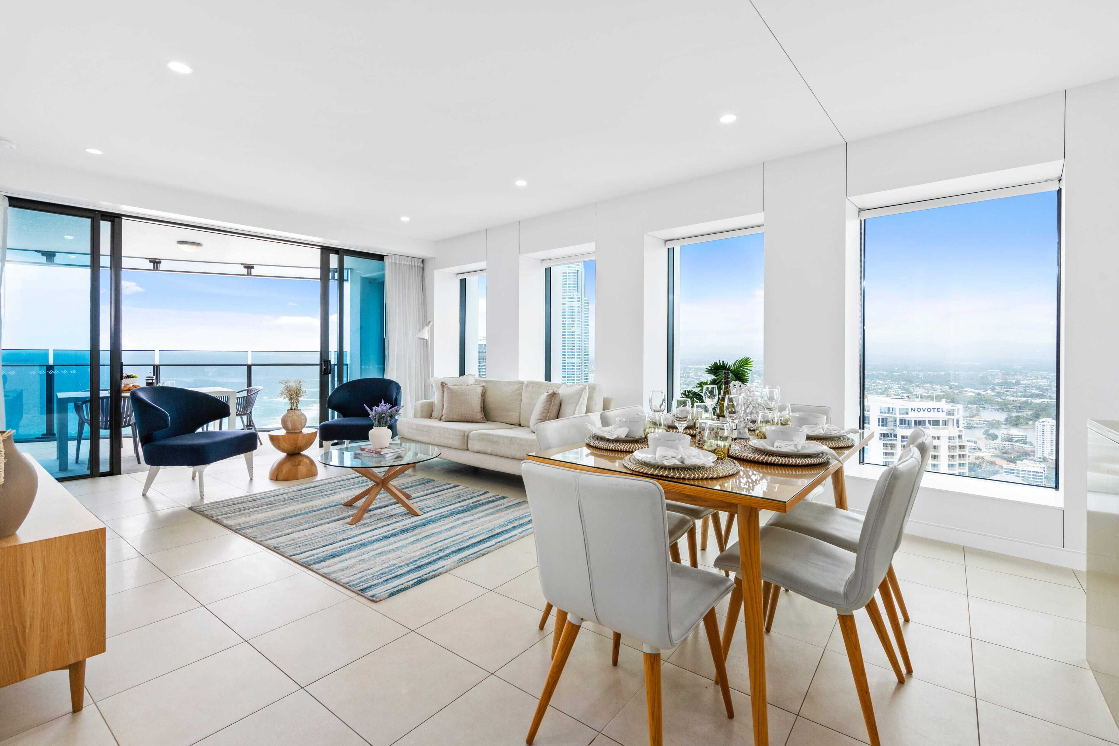 A modern living room with a dining area, large windows, and a view of the city.