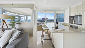 Une cuisine moderne dotée d’un grand îlot central, de tabourets de bar et offrant une vue sur la ville.