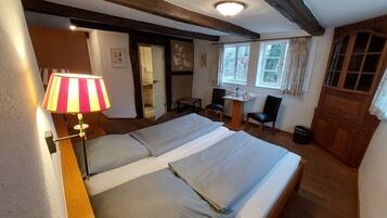 Ein Hotelzimmer mit einem großen Bett, einem Schreibtisch mit zwei Stühlen, einer Lampe und Blick nach draußen durch ein Fenster.