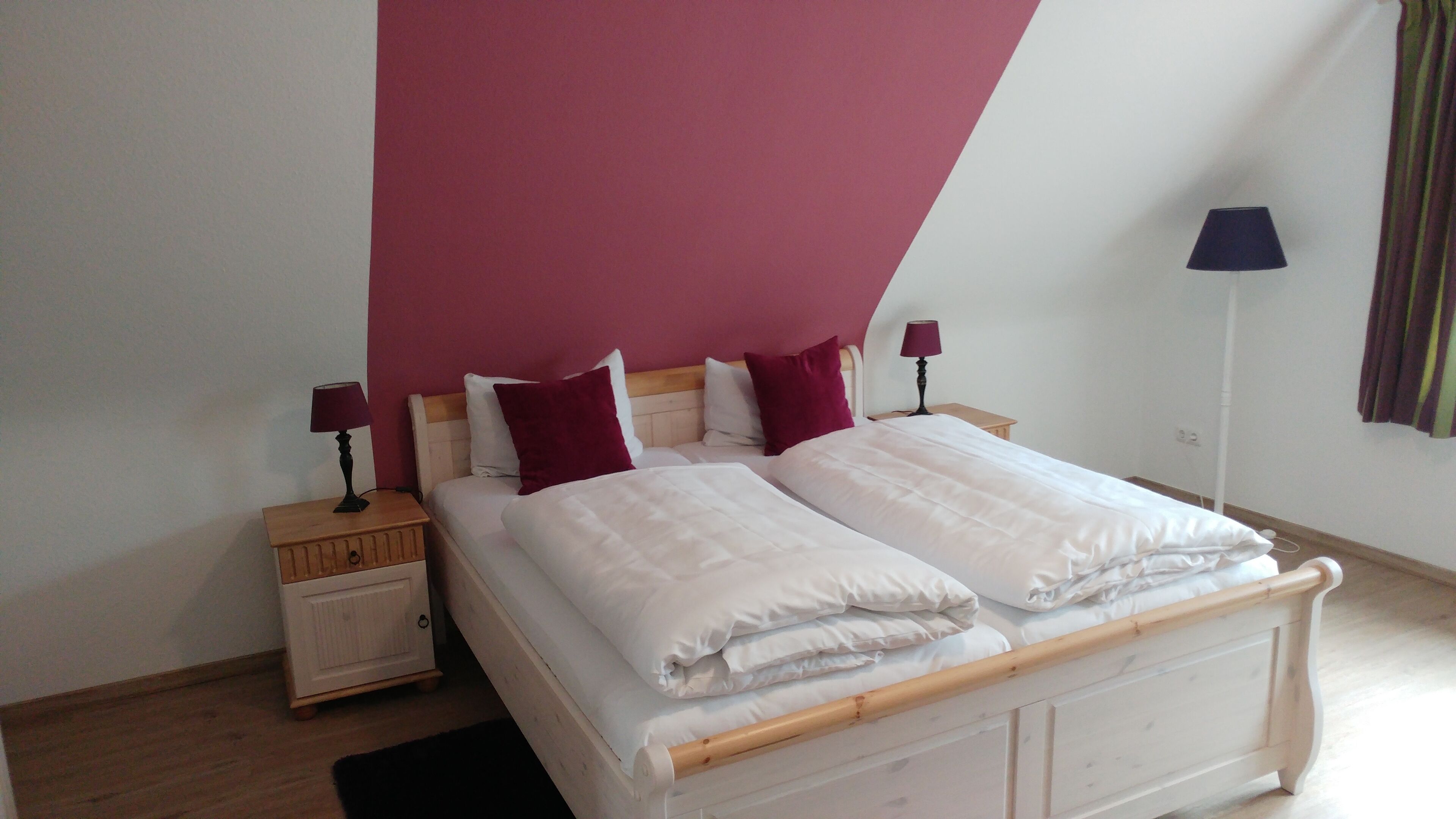 Une chambre à coucher avec un lit, deux tables de chevet, une lampe et une petite table.