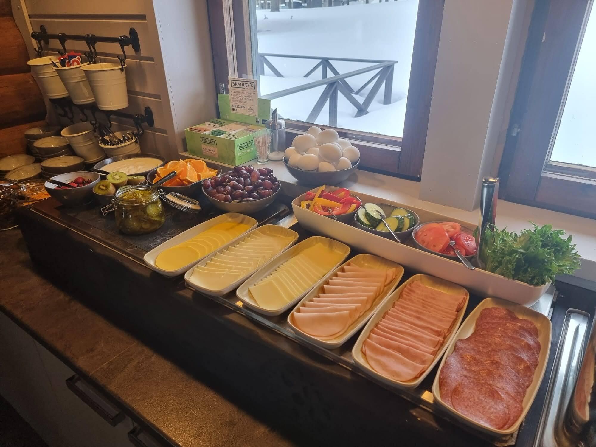 A buffet with various food options including fruits, cheeses, and meats.