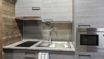 Una cocina moderna con un lavamanos de acero inoxidable, un microondas integrado y paneles de madera en los armarios superiores.