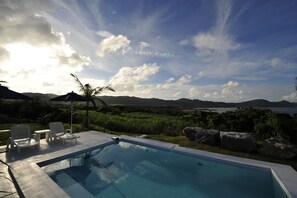 A swimming pool with lounge chairs and a view of mountains and a lake. - Windy Earth SILENT CLUB (Ishigaki)