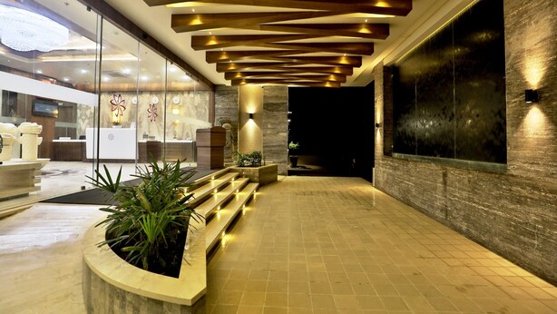A modern lobby with a reception desk, seating area, and a large water feature. - VITS Devbhumi, Dwarka (Dwarka)