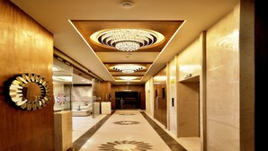 A hotel corridor with chandeliers, a marble floor, and a reception area. - VITS Devbhumi, Dwarka (Dwarka)