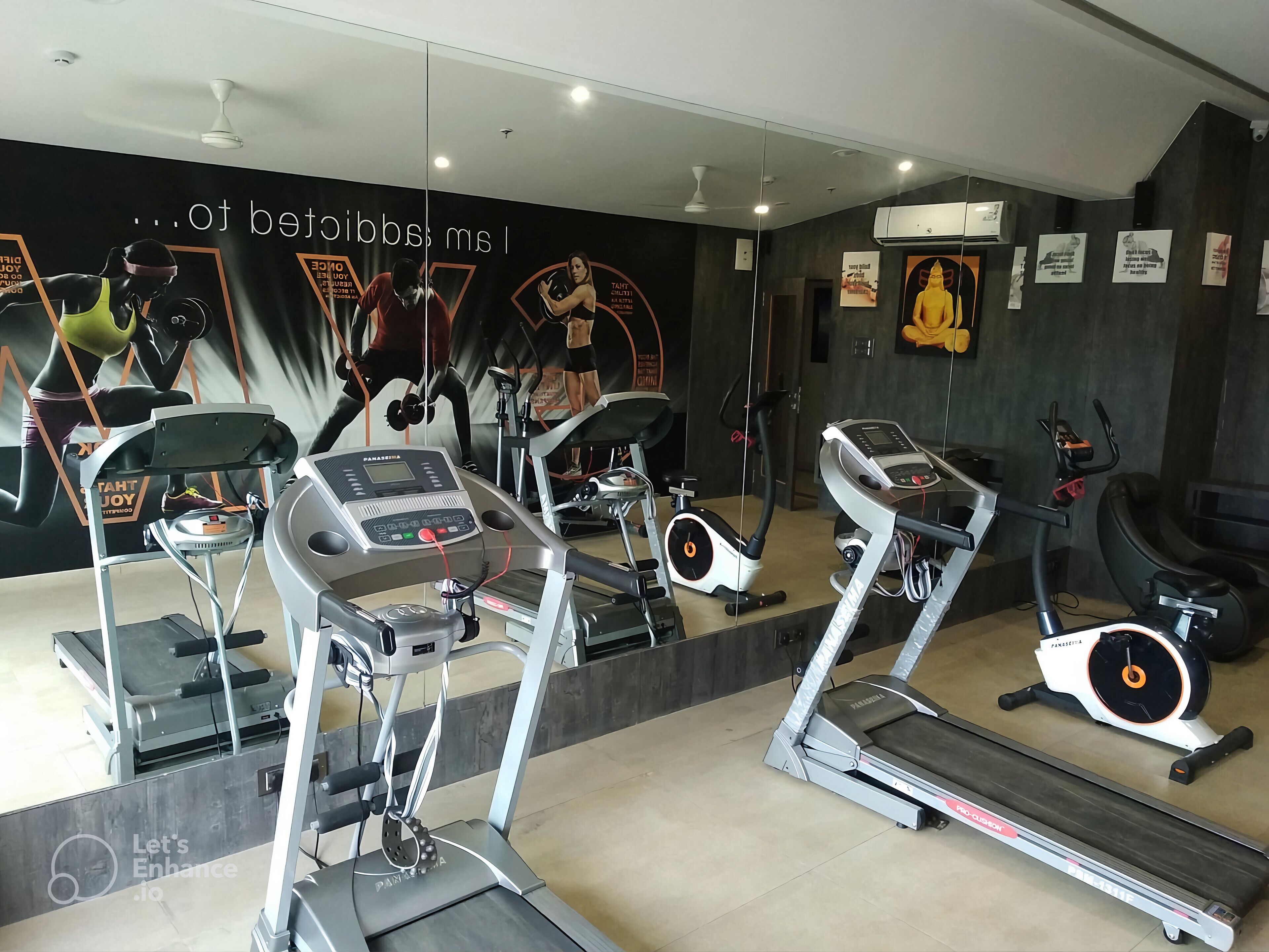 A gym with treadmills, stationary bikes, and a mirrored wall.