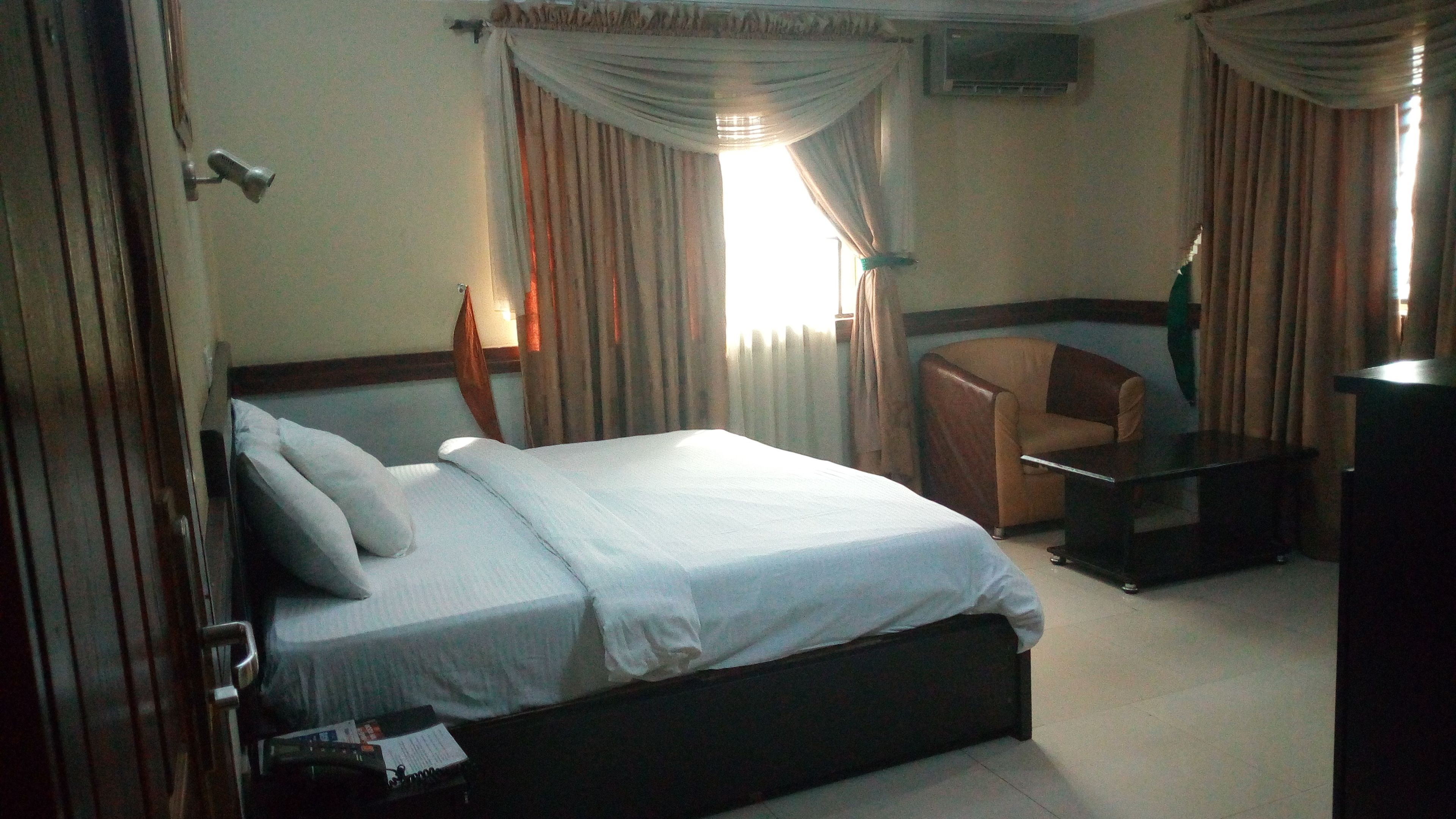 Une chambre d’hôtel avec un lit, un bureau, une chaise et des rideaux.
