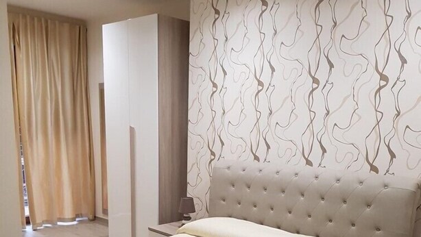A spacious bedroom with a large bed, a wardrobe, and a nightstand. - La Suite (Cassino)