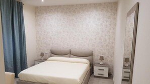 A modern bedroom with a large bed, bedside tables, and a mirror. - La Suite (Cassino)