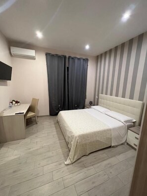 A bedroom with a bed, bedside table, chair, desk, and curtains. - La Suite (Cassino)